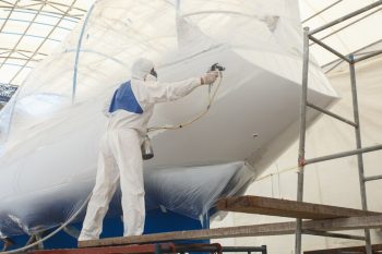 man-with-white-uniform-spraying-paint-boat_30478-3683